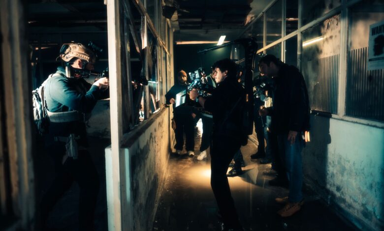 A cinematic scene capturing actors filming an intense action sequence in a dimly lit warehouse.