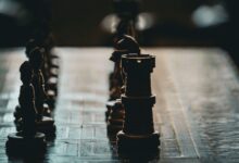 Close-up of a chess board with dramatic lighting and focus on a rook piece.