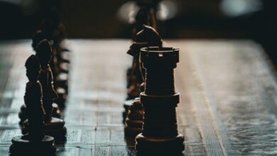 Close-up of a chess board with dramatic lighting and focus on a rook piece.