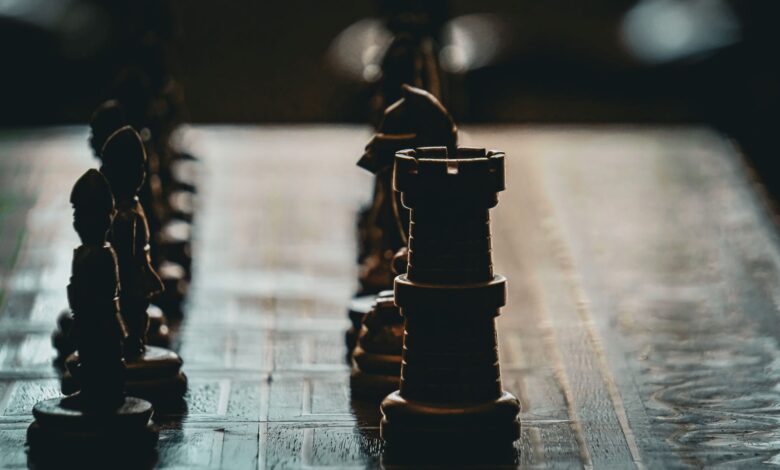 Close-up of a chess board with dramatic lighting and focus on a rook piece.