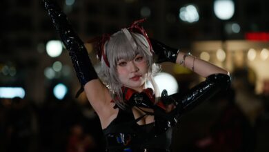 A cosplayer in detailed costume poses confidently in a lively night scene.