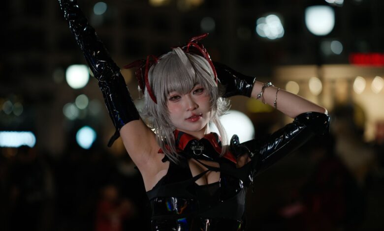A cosplayer in detailed costume poses confidently in a lively night scene.