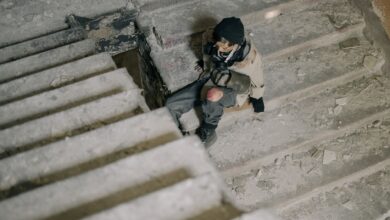 Young man in abandoned building, sitting on stairs, in post-apocalyptic setting.