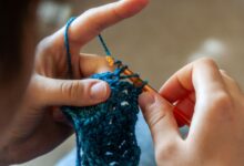 Detailed image of hands crocheting a blue yarn piece with a crochet hook. Ideal for crafting themes.