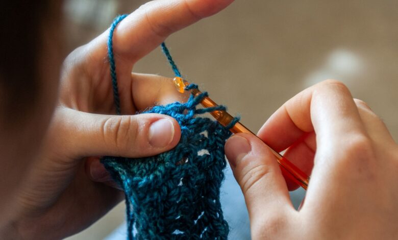 Detailed image of hands crocheting a blue yarn piece with a crochet hook. Ideal for crafting themes.