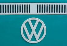 Close-up of a vintage Volkswagen emblem on a teal van, showcasing classic design and color.
