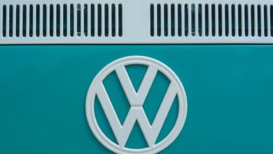 Close-up of a vintage Volkswagen emblem on a teal van, showcasing classic design and color.