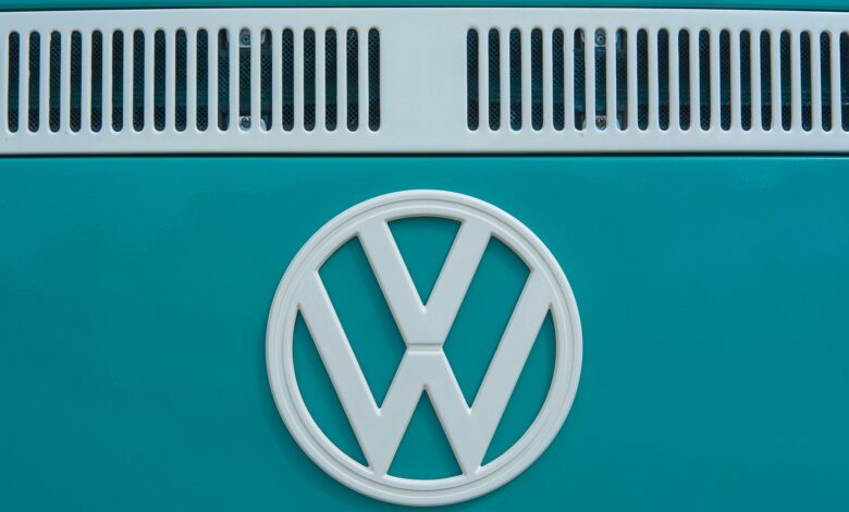 Close-up of a vintage Volkswagen emblem on a teal van, showcasing classic design and color.