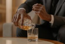 Close-up of a man elegantly pouring whiskey into a glass at a luxurious indoor setting.