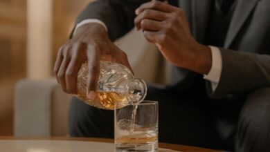 Close-up of a man elegantly pouring whiskey into a glass at a luxurious indoor setting.