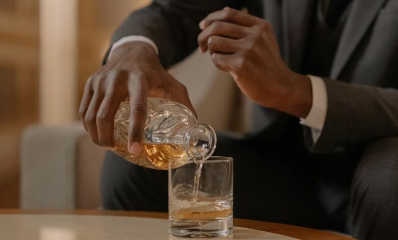 Close-up of a man elegantly pouring whiskey into a glass at a luxurious indoor setting.