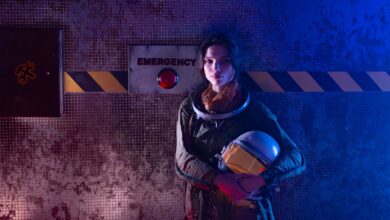 A futuristic woman astronaut standing near an emergency button in a sci-fi setting.