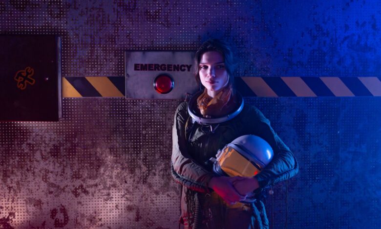 A futuristic woman astronaut standing near an emergency button in a sci-fi setting.