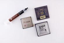High-angle view of AMD processors and Noctua thermal paste on a white surface.