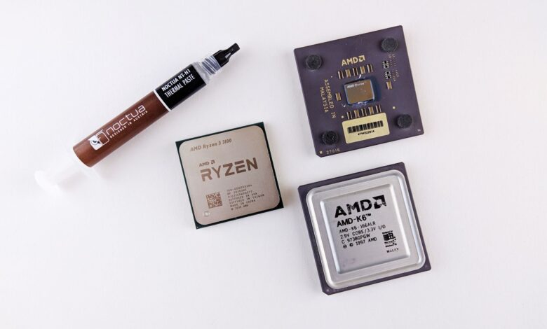 High-angle view of AMD processors and Noctua thermal paste on a white surface.