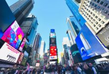 Vibrant daytime view of Times Square, showcasing iconic billboards and bustling crowd in New York City.