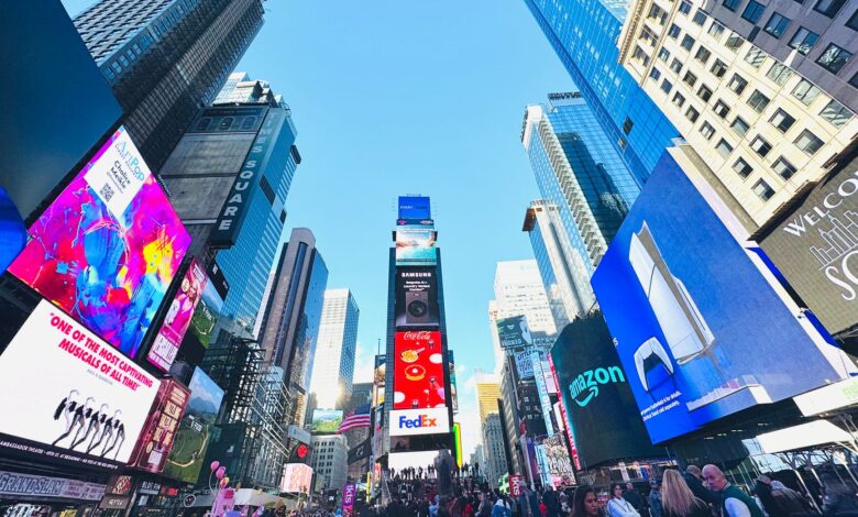 Vibrant daytime view of Times Square, showcasing iconic billboards and bustling crowd in New York City.