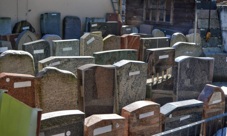Diverse gravestones on display outdoors, showcasing different designs and materials ready for selection.