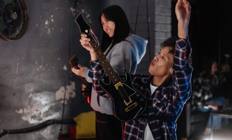 Two friends have fun playing a guitar simulation game indoors.