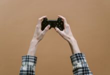 Close-up of hands holding a game controller against a brown background, perfect for gaming themes.