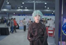 Cosplayer with icy blue wig poses at a vibrant convention center event.