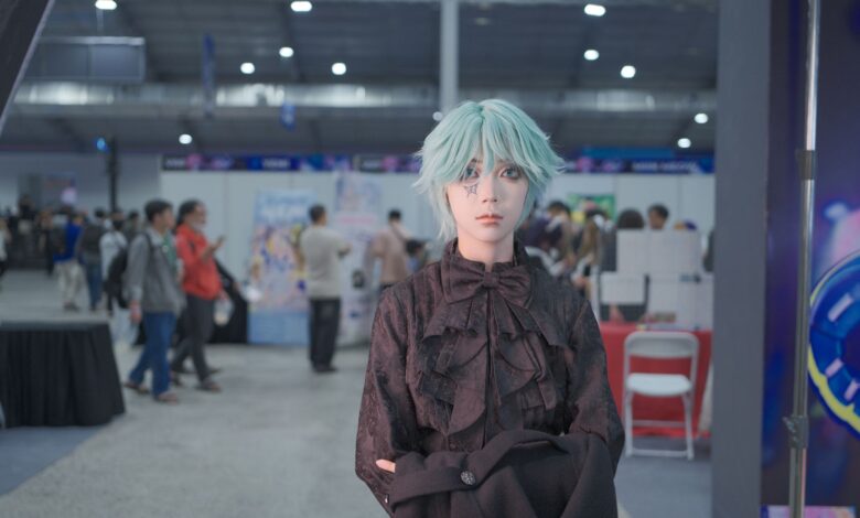 Cosplayer with icy blue wig poses at a vibrant convention center event.
