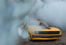 1969 Camaro drifting on pavement with smoke engulfing the car, showcasing its power.