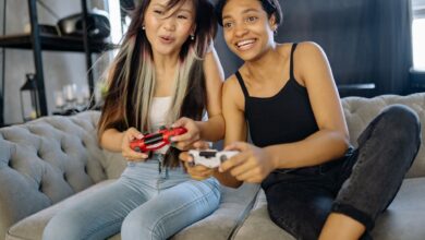 Two women playing video games together, smiling and having fun indoors.