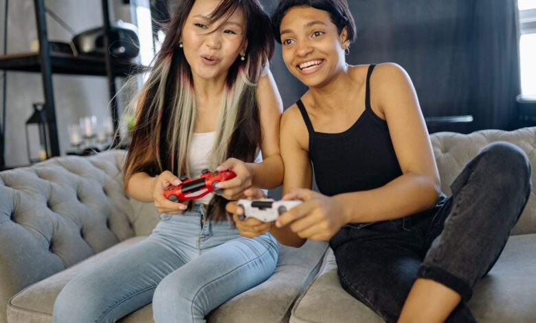 Two women playing video games together, smiling and having fun indoors.
