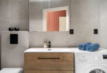 Contemporary bathroom featuring a sleek wooden vanity, washing machine, and modern fixtures.