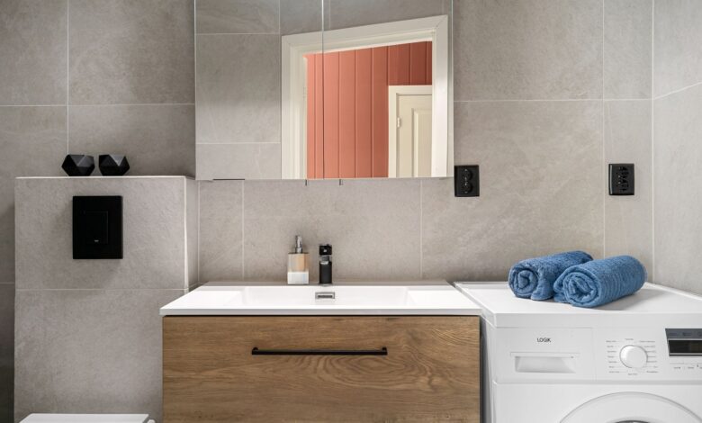 Contemporary bathroom featuring a sleek wooden vanity, washing machine, and modern fixtures.
