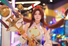 Cosplayer in elaborate costume poses in vibrant, colorful arcade environment.