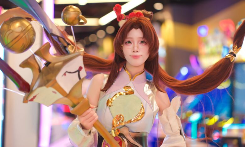Cosplayer in elaborate costume poses in vibrant, colorful arcade environment.