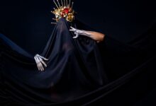 A dramatic portrait featuring a person with a gold headdress and black veil, set against a dark background.