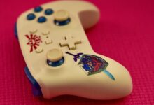 Close-up of a gaming controller with a unique design on a vibrant pink surface.