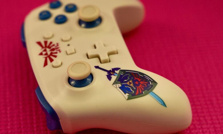 Close-up of a gaming controller with a unique design on a vibrant pink surface.
