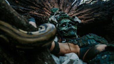 A mysterious figure in an ancient costume with a skull mask, surrounded by nature.
