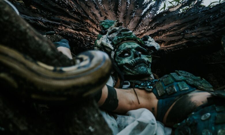 A mysterious figure in an ancient costume with a skull mask, surrounded by nature.