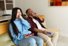 Happy couple enjoying video games together on a cozy living room couch, experiencing laughter and bonding.