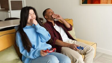 Happy couple enjoying video games together on a cozy living room couch, experiencing laughter and bonding.