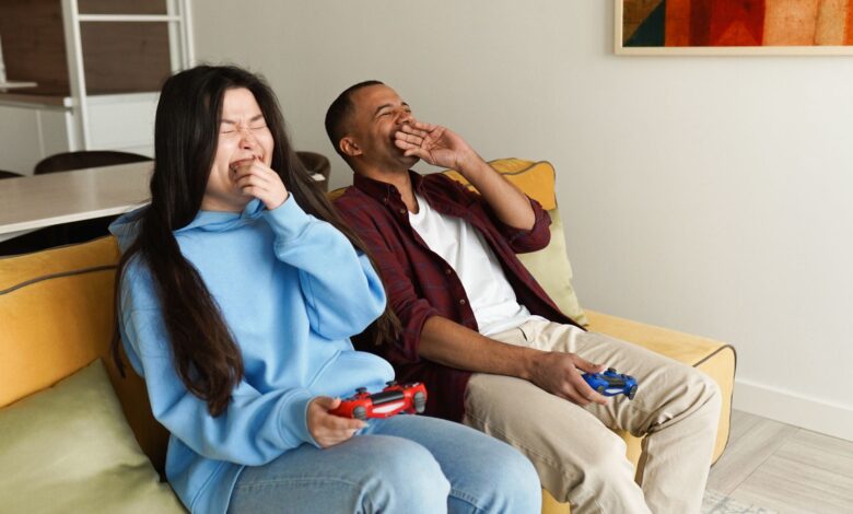 Happy couple enjoying video games together on a cozy living room couch, experiencing laughter and bonding.