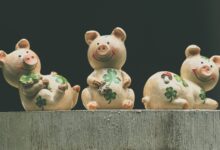 Set of three ceramic pig figurines adorned with clover, symbolizing luck and prosperity.