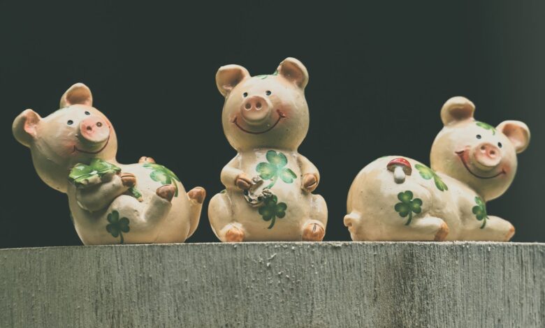 Set of three ceramic pig figurines adorned with clover, symbolizing luck and prosperity.