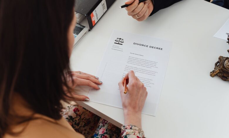 A person signing a divorce decree document with focus on hands and paper.