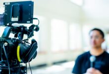 Professional video camera setup focusing on an interview with blurred subject in the background.
