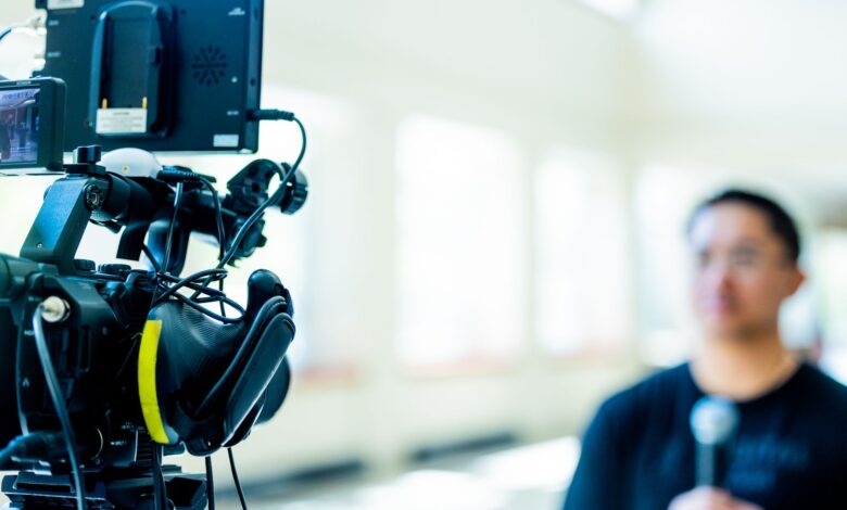 Professional video camera setup focusing on an interview with blurred subject in the background.