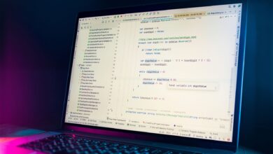 A laptop screen showing a code editor with visible programming code in a dimly lit environment.