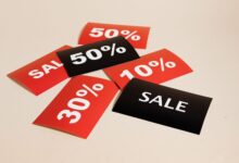 Red and black sale tags showing various discount percentages on a beige background.
