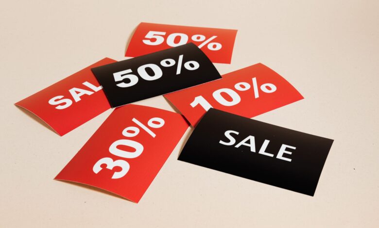 Red and black sale tags showing various discount percentages on a beige background.
