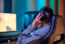 A man in headphones gaming on a computer at a stylish desk setup.